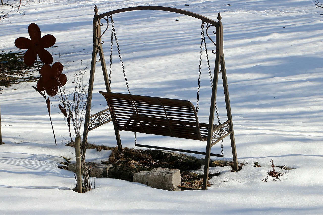 Hollywoodschaukel aus Metall im verschneiten Garten