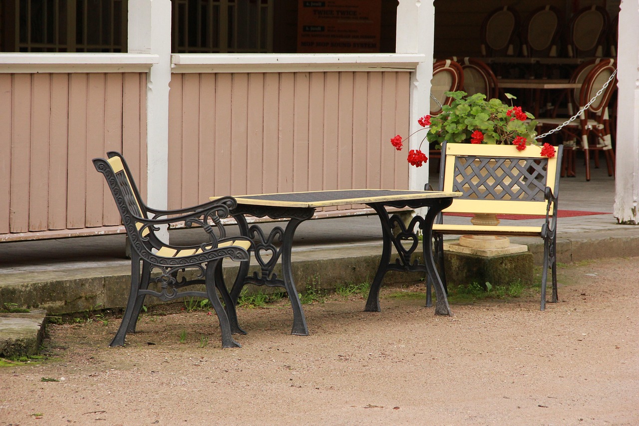 Gartenbänke und Tisch mit Gestell aus Gusseisen vor einem Holzhaus