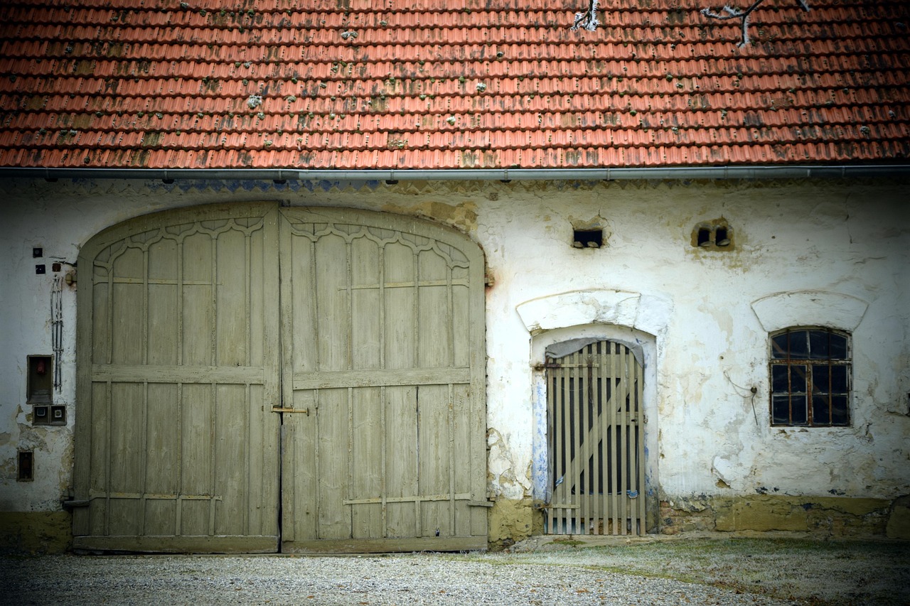 Altes zweiflügeliges Holztor an einem Bauernhaus mit Ziegeldach