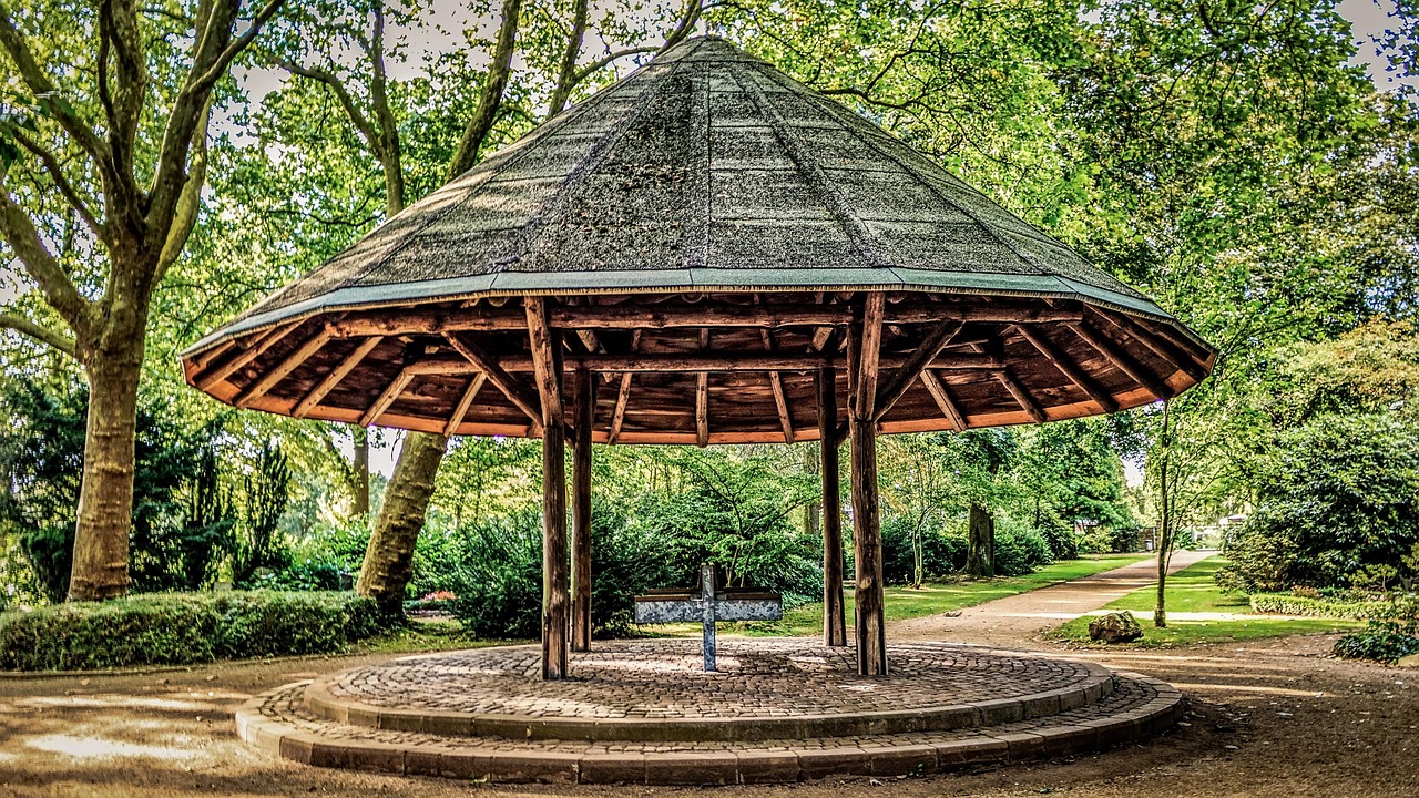 Offener Holzpavillon mit kegelförmigem Dach in einer Parkanlage