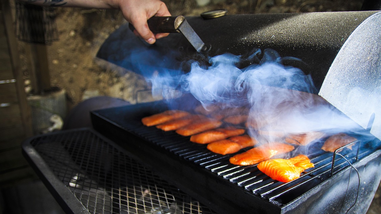 Geöffneter Smoker-Grill mit Lachsfilets im Rauch