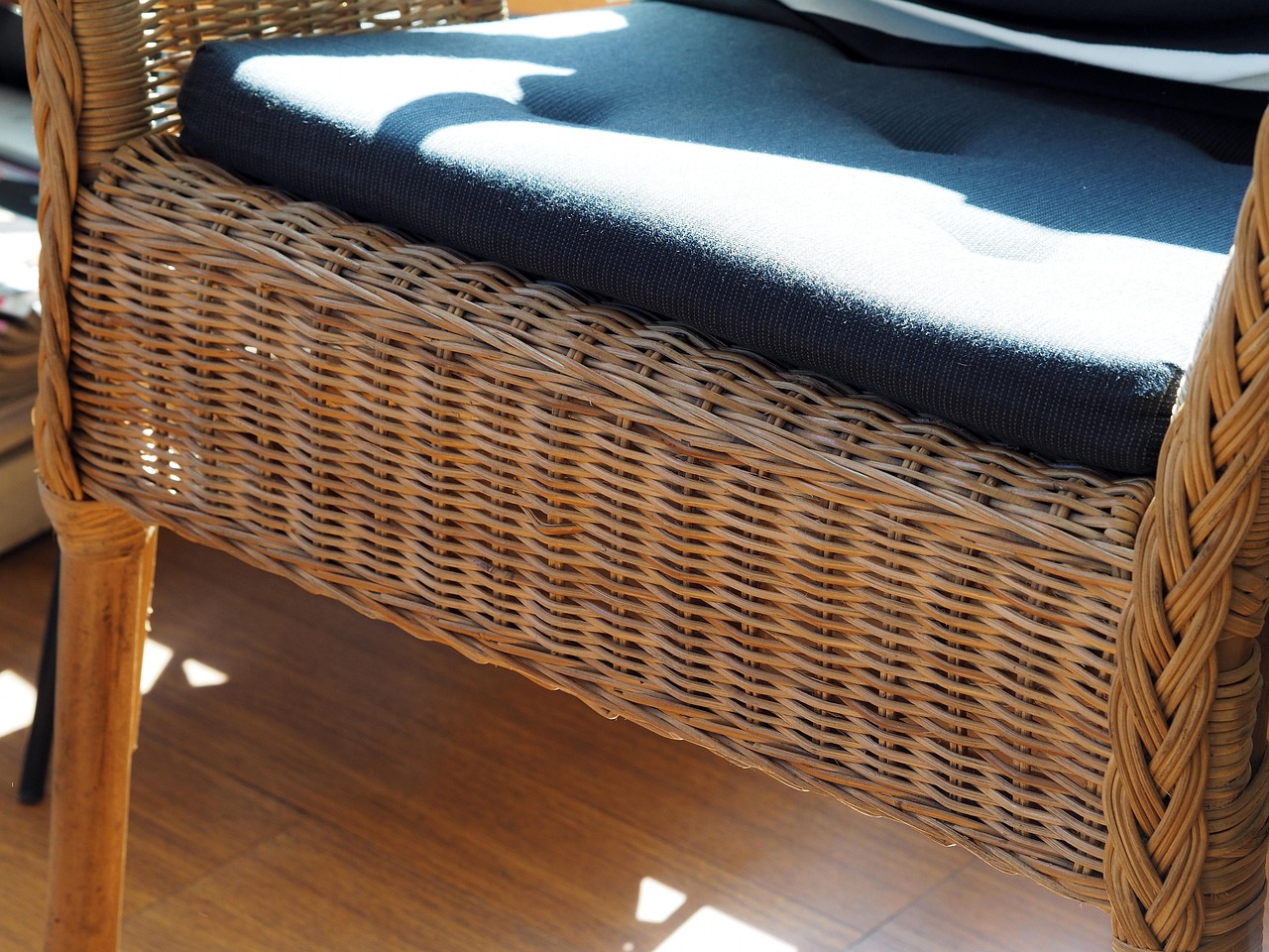 Geflochtener Rattansessel mit dunklem Sitzpolster im Detail