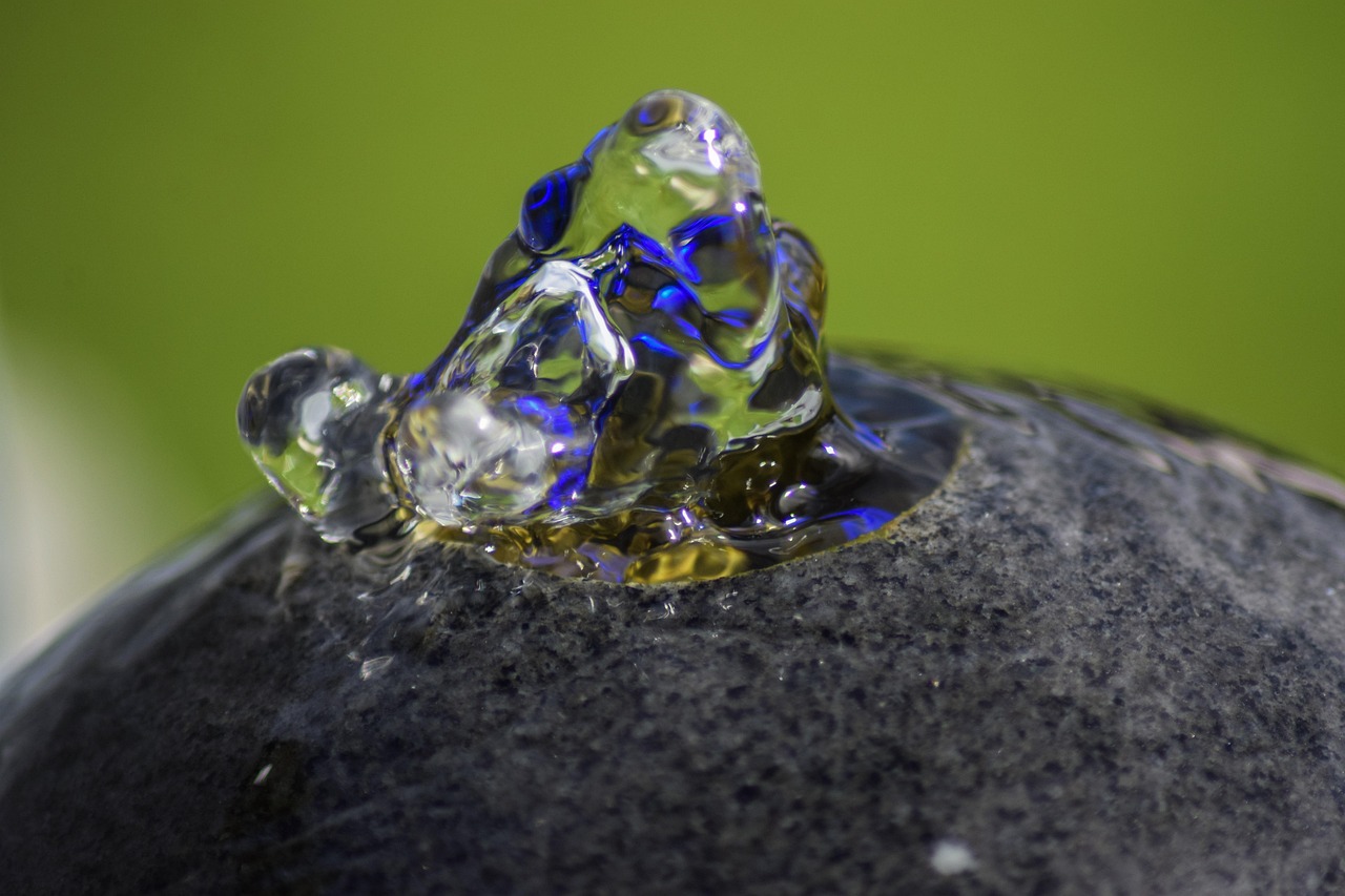 Sprudelnder Quellstein: Wasser perlt aus einer dunklen Steinkugel