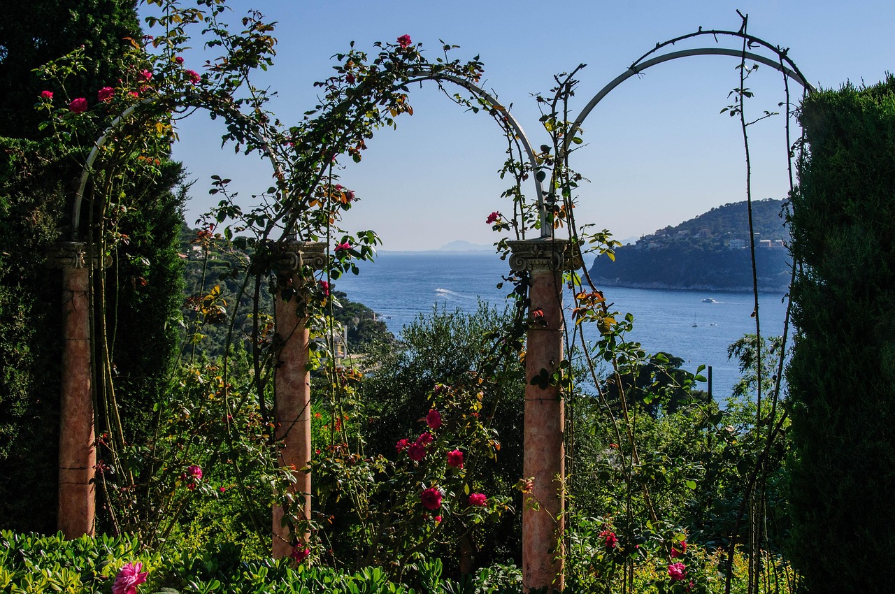 Rosenbögen aus Metall mit blühenden Kletterrosen in einem Garten am Meer